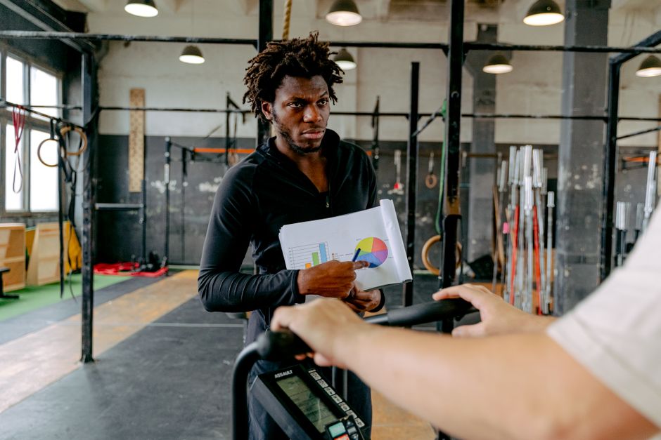 A personal trainer guides a client during a workout session at the gym.